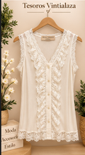 A cream colored sleeveless lace trimmed top with a button front center and ruffled lace details